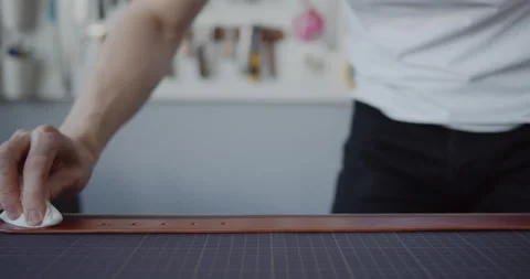 Leather worker oiling a leather belt during manufacturing process close-up Stock Footage 146138878