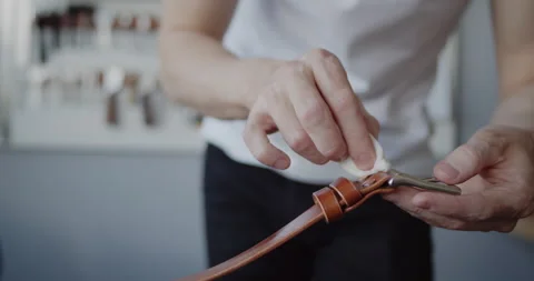 Leather worker oiling a leather belt during manufacturing process close-up Stock Footage 146138926