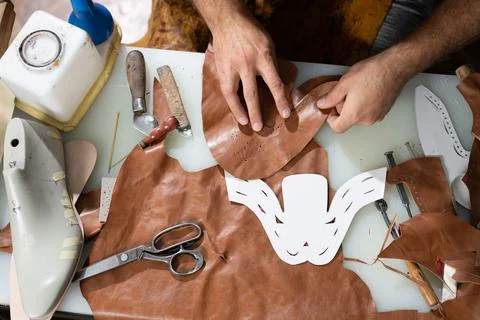 Leather workshop scene of hands crafting a decorative mask with tools and Stock Photos