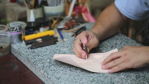 The leatherworker is drawing patterns on the sheet of leather. 스톡 동영상 194479192