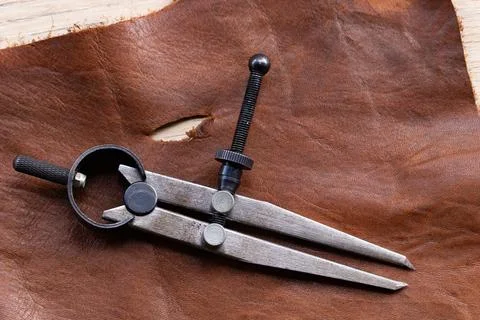 Leatherworking tools, compass and materials for artisanal design. Photos
