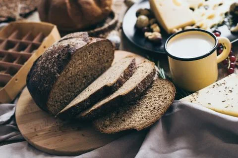 Leaves of bread lying on beige background with a yellow stylish cup of milk and 스톡 사진