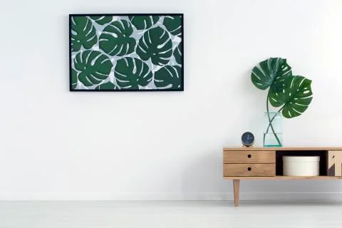Leaves poster on white wall in living room interior with wooden cupboard. Rea Stock Photos