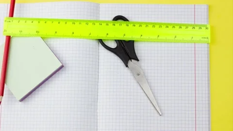 Leaving school supplies with a checkered notebook on a pastel yellow background Stock Footage 138650613