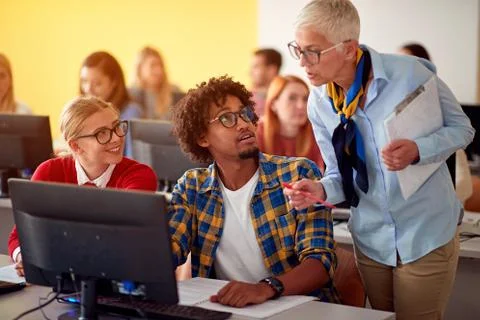 Lecturer in computer class assisting student on university. Stock Photos