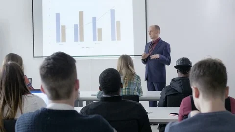 Lecturer presenting charts to many college students in lecture Stock Footage