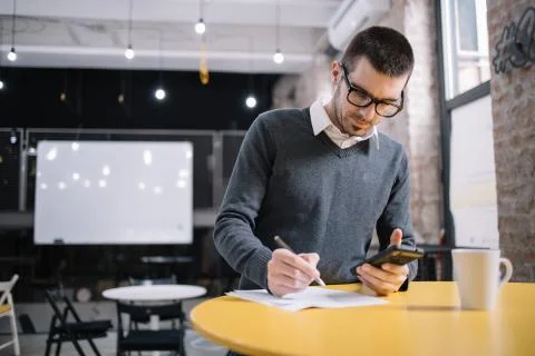 Lecturer taking notes on table with phone Stock Photos