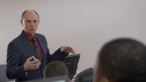 Lecturer wearing a suit presenting a topic to multi-ethnic students Stock Footage 69930136