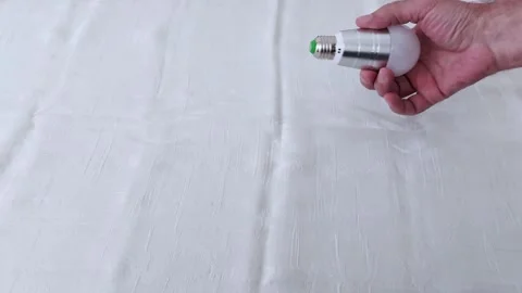 LED Bulb in Hand Over Soft Fabric- Tactile Energy Detail Shot Video stock 311752288