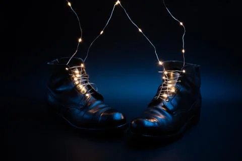 Led bulbs laces slip into old black military shoes on a blue background Stock Photos