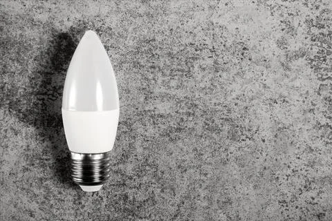 LED energy-saving lamp with E27 screw cap base in form of candle, on gray Stock Photos