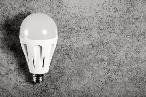 LED energy-saving lamp with E27 screw cap base on gray background with copy Stock Photos