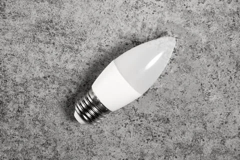 LED energy-saving lamp with E27 screw cap base in form of candle, on gray Stock Photos