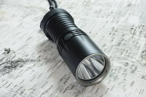 Led flashlight laying on birch bark Stock Photos