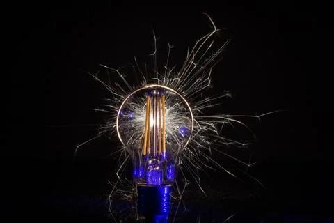 LED lamp with sparkler in front of black background Stock Photos