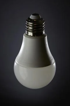 LED light bulb on dark gradient background with soft magenta spotlight Stock Photos