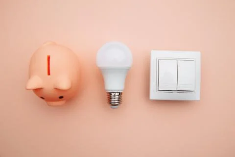 LED light bulb, switch on and pink piggy bank. Power energy economy concept Stock Photos