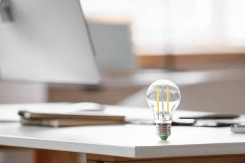 Led light bulb on white desk, innovation and energy efficiency, business idea Stock Photos