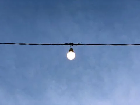 Led Light Bulb on the wire with blue cloudy sk Stock Photos