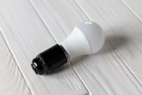 LED light in a dark base. Lies on a wooden background. white color. Stock Photos