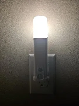 LED Night Light Plugged Into Electrical Wall Outlet Illuminating Dark Inter.. Stock Photos