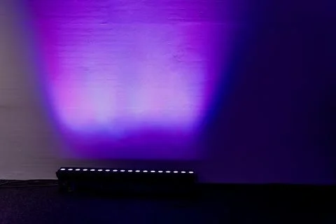 LED stage light bar projecting purple and blue illumination onto wall Foto stock