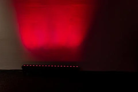 LED stage light bar projecting red illumination onto wall Foto stock