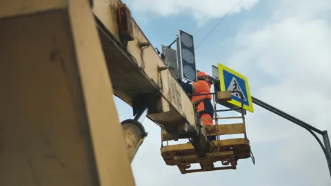 LED technology. A worker in the elevator cradle fixes the LED traffic light Stock-Footage 141087511