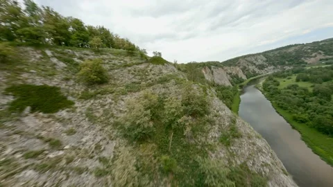 The ledge of the rock, overgrown with shrubs hangs over the river. A small wild Stock Footage 158304451