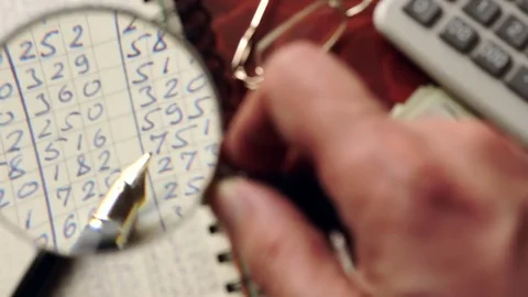 Ledger papers are watched with magnifier. Financial accounting concept. Stock Footage 73233302