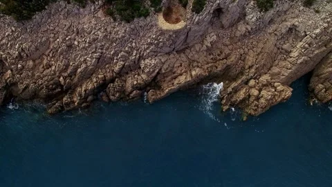 Ledges of a rocky cliff over a deep clear blue sea. Drone Stock Footage 274177273