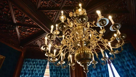 Lednice, Czech Republic - July 19, 2026: A brass candle chandelier below a dark Stock Footage 342286777