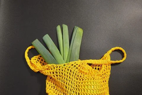 Leek in a bag for vegetables on a black background. Stock Photos