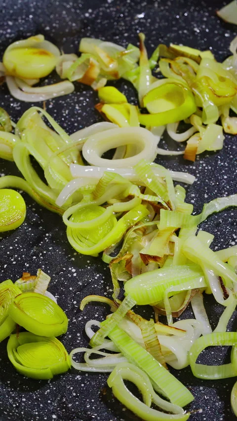 Leeks cooking beautifully Tender leeks with crispy edges and savory aroma in pan Stock Footage 329275897