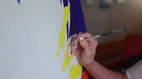 Left Angle Medium Shot of Artist's hand painting red on an unfinished piece Stock Footage 57222093