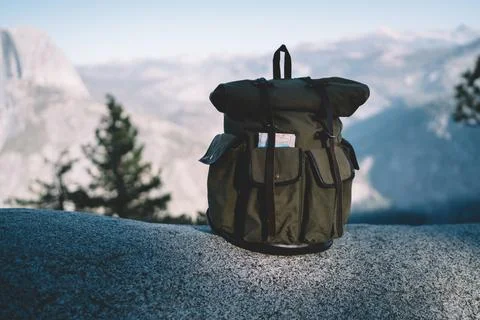 Left backpack on stone against mountain ridge Stock Photos