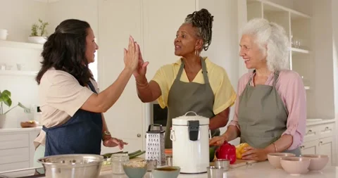 Left cook lifting hand sparking high-five, three women joining, then prepping Stock Footage 341091269