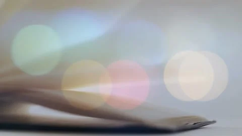 Left-edge lift starting thin stack pages lifting and fanning right over soft Stock Footage 334466288