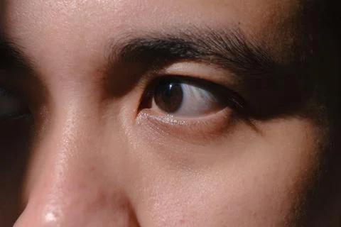 A left eye of a man looking to the right side with some shadows Stock Photos