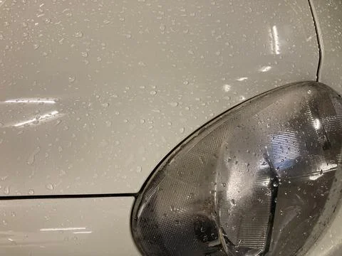The left-front light of a white car with many raindrops Stock Photos