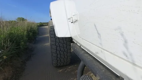 LEFT FRONT WHEEL ON JEEP DRIVING DIRT ROAD Video stock 104838701