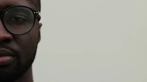 Left half of face of guy in glasses on white background. Young African man Stock Footage 81839478