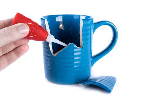 Left hand applying glue to a broken ceramc coffee cup Stock Photos