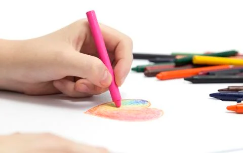 Left hand drawing a heart shape with colored crayons pastels Stock Photos