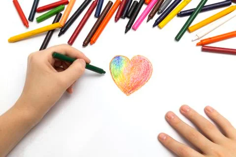 Left hand drawing a heart shape with colored crayons pastels Stock Photos