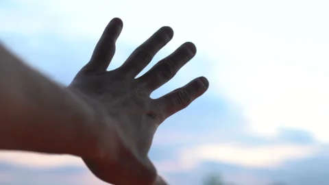 Left hand extended towards the blue sky in attempt to reach the clouds Stock Footage 96086442