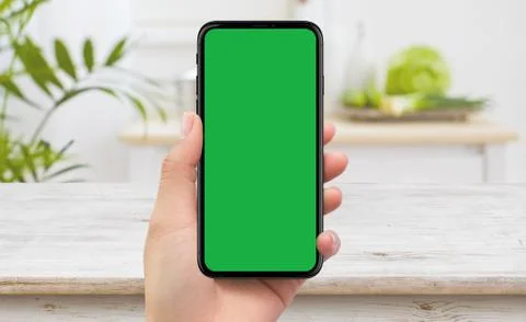 Left hand holding black mobile smartphone device green screen in kichen Stock Illustration