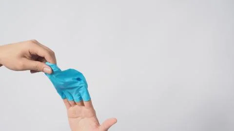 Left hand is pulling right hand with blue latex gloves on white background. Stock Photos