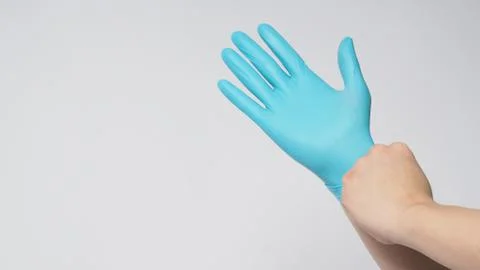 Left hand is pulling right hand wearing blue latex gloves on white background Stock Photos