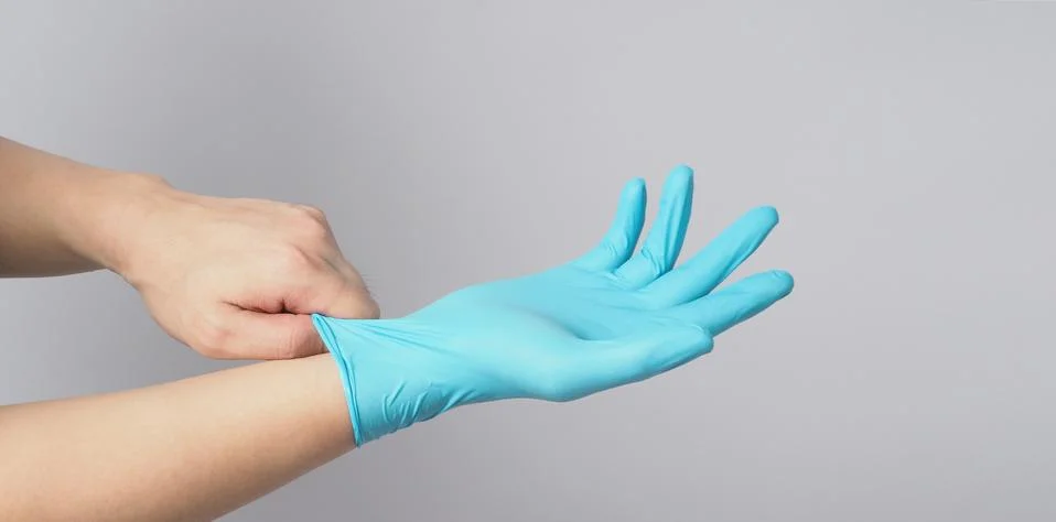 Left hand is pulling right hand wearing blue latex gloves on white background Stock Photos